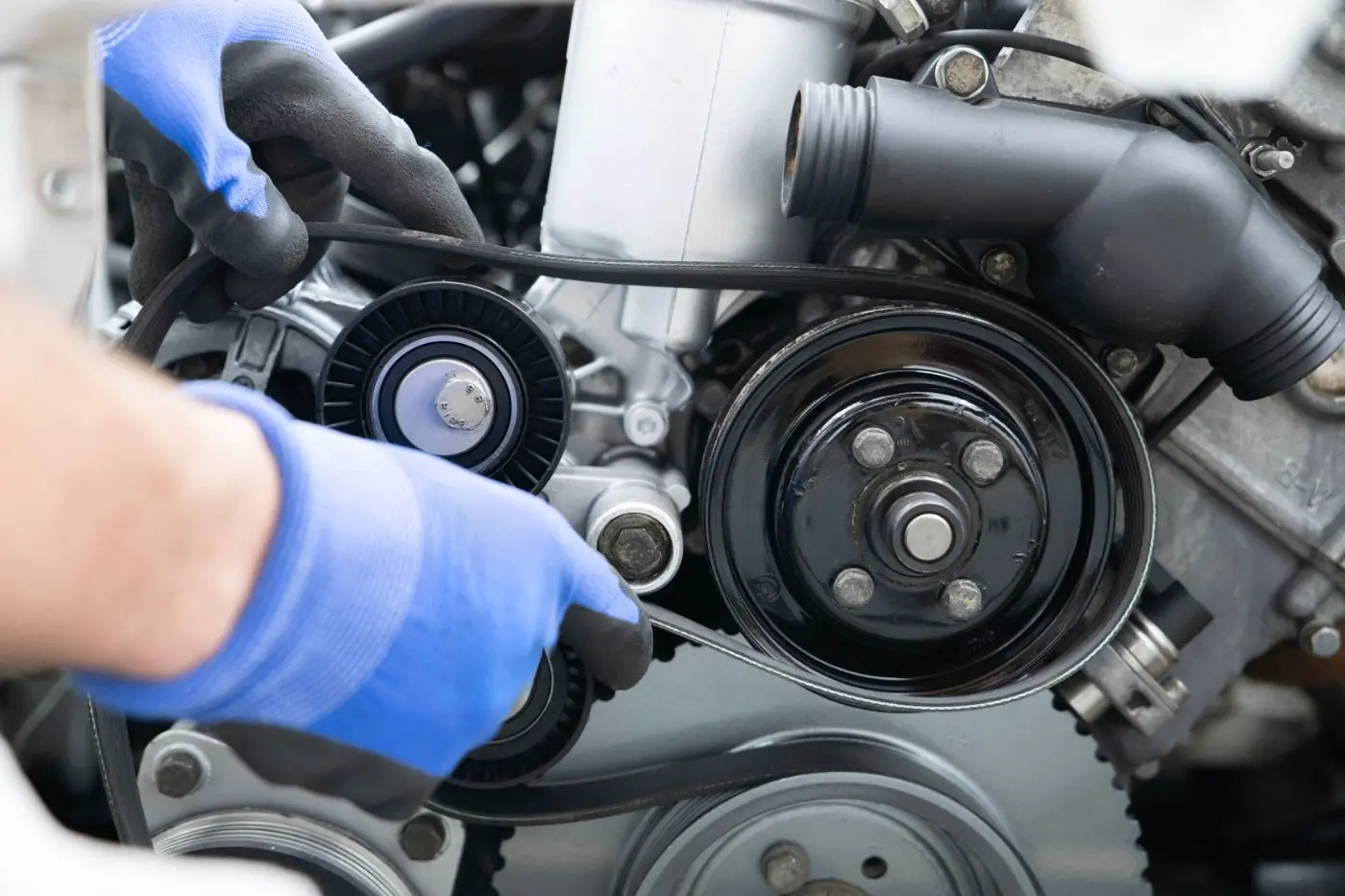 Eldivenli usta, motor bölmesinde kayış ve gergi rulmanı üzerinde çalışıyor