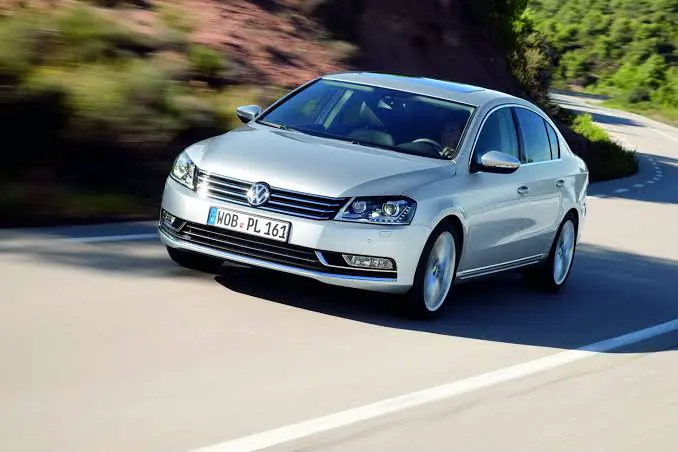 Yolda seyir hâlindeki gümüş Volkswagen Passat B7 sedan
